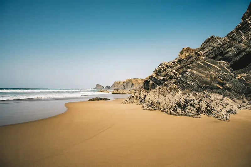 A golden beach below rocky cliffs on the Algarve coast