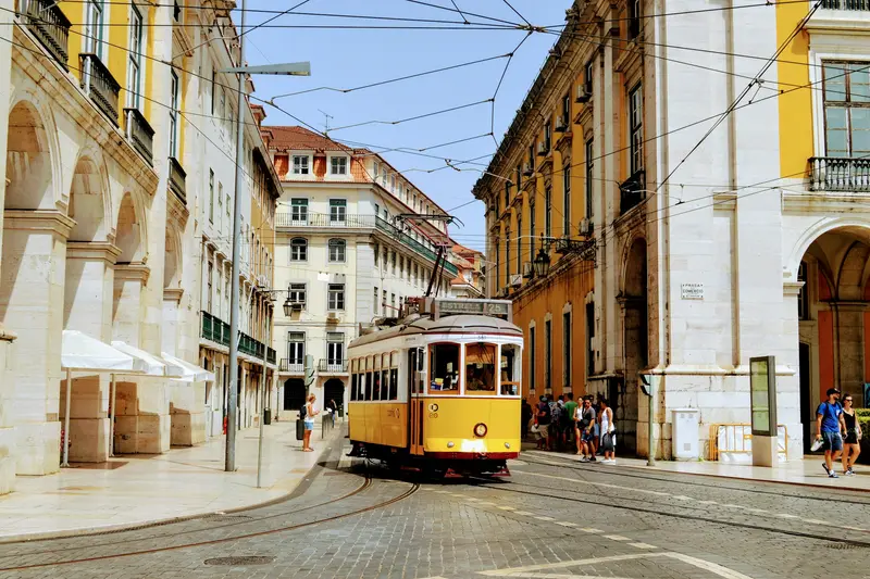 A yellow tram in a street of historic buildings in Lisbon