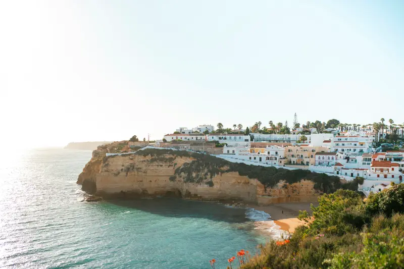 Whitewashed houses on a clifftop above a sandy bay on the Portuguese coast