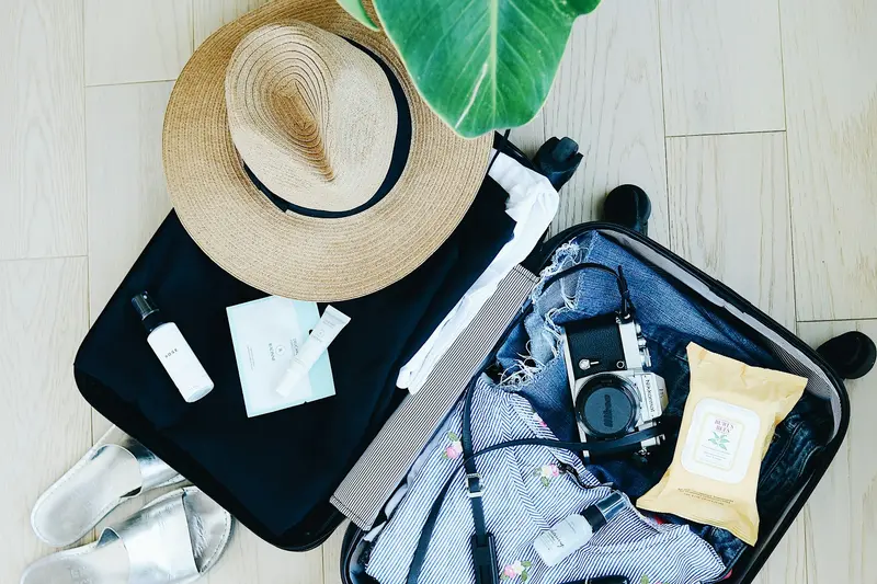 An open suitcase packed with clothes, a sun hat and travel essentials